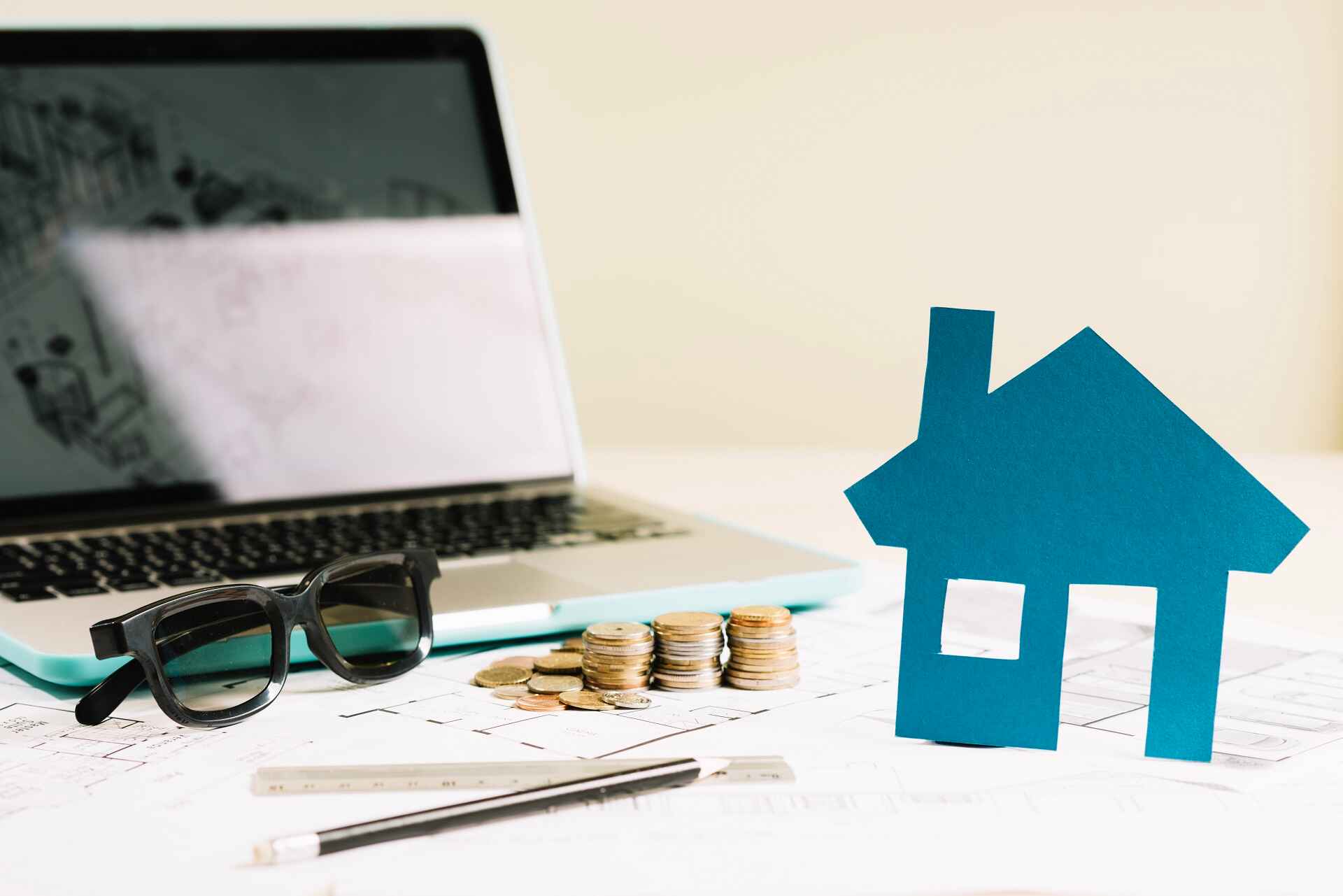 Mini house model with floor plan and laptop, symbolizing mortgage refinance planning